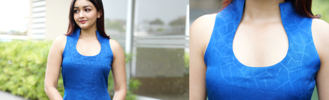 Woman wearing a blue sleeveless top with a close-up of the neckline.