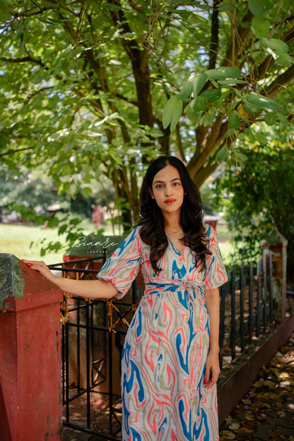 Woman in a patterned dress standing outdoors with greenery in the background