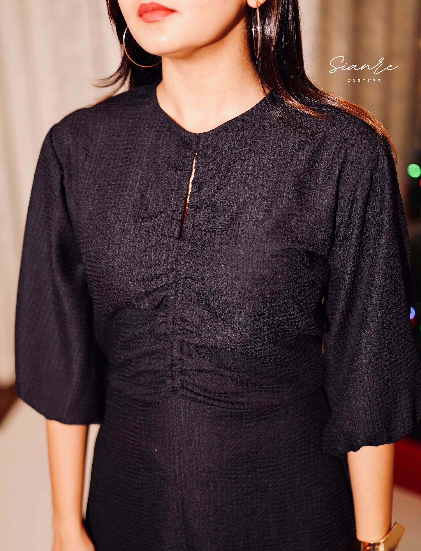 Black dress with textured pattern worn by a person, brand 'Sivan' visible