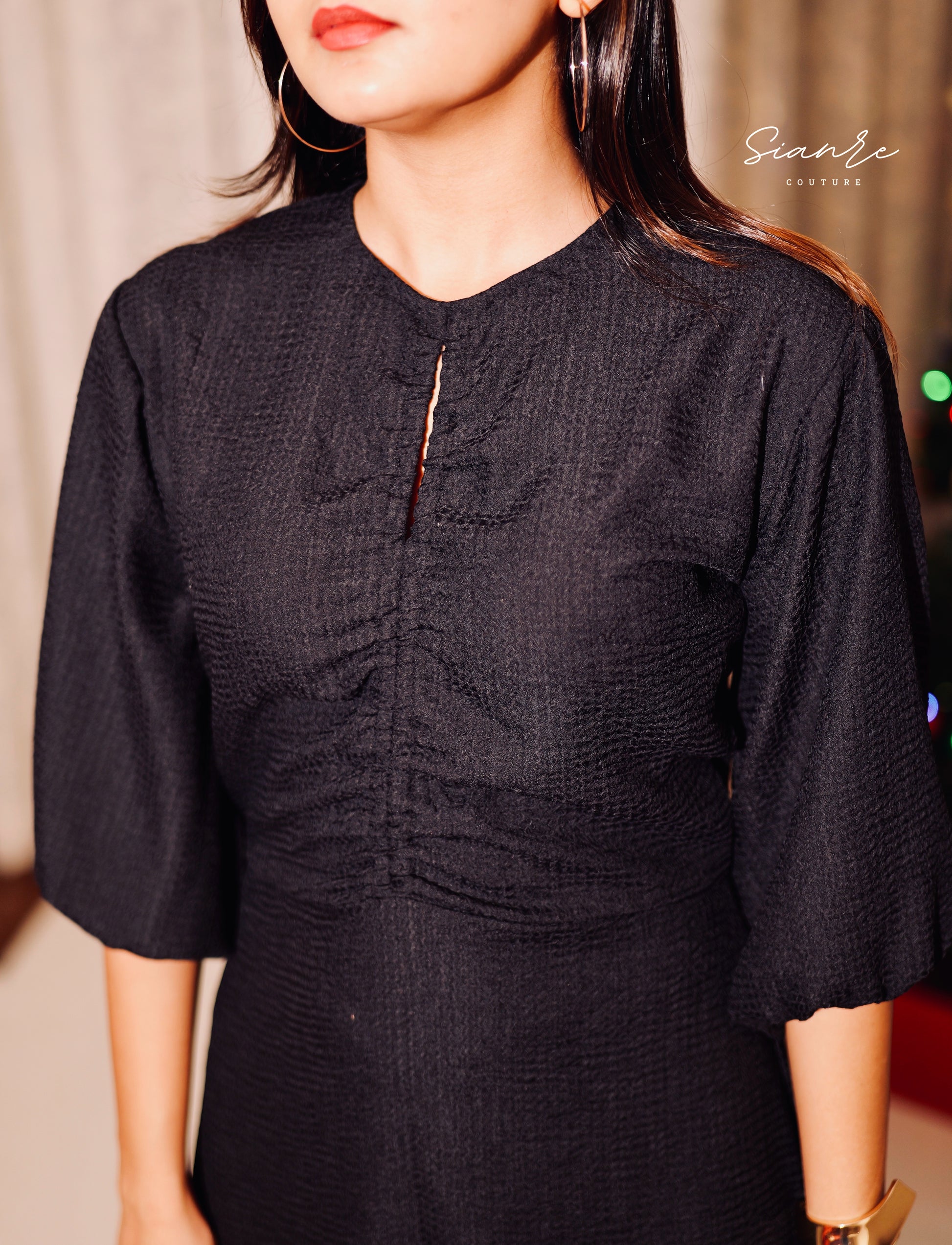 Black dress with textured pattern worn by a person, brand 'Sivan' visible