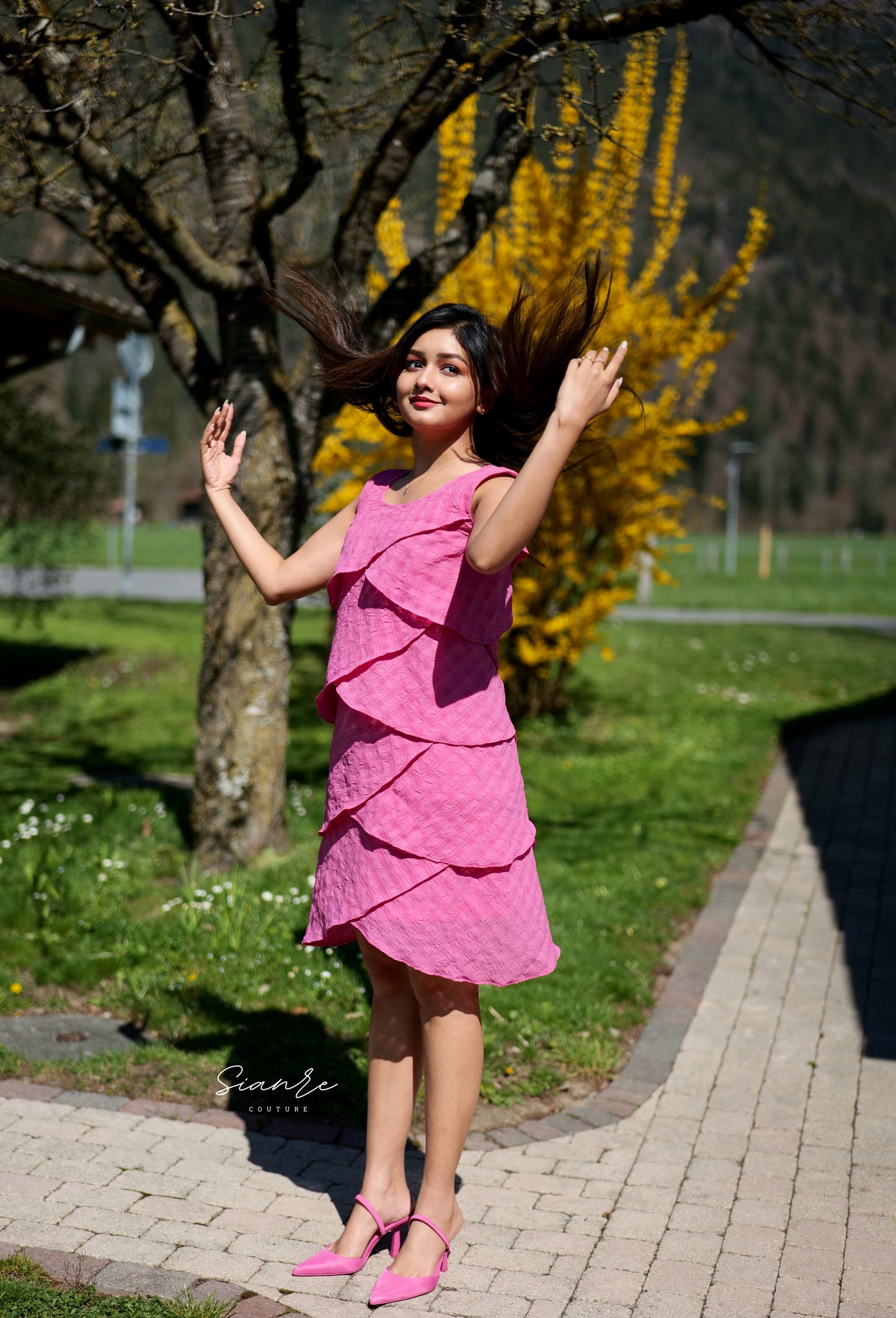 Woman in a pink dress standing outdoors with trees and grass in the background