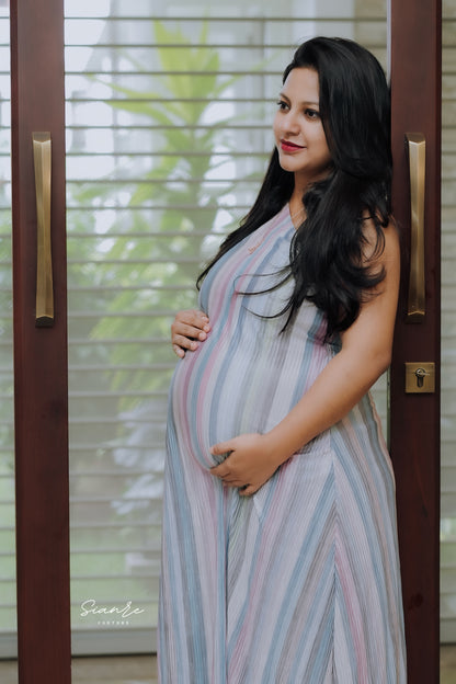 Pregnant woman in a striped dress standing in front of a glass door.